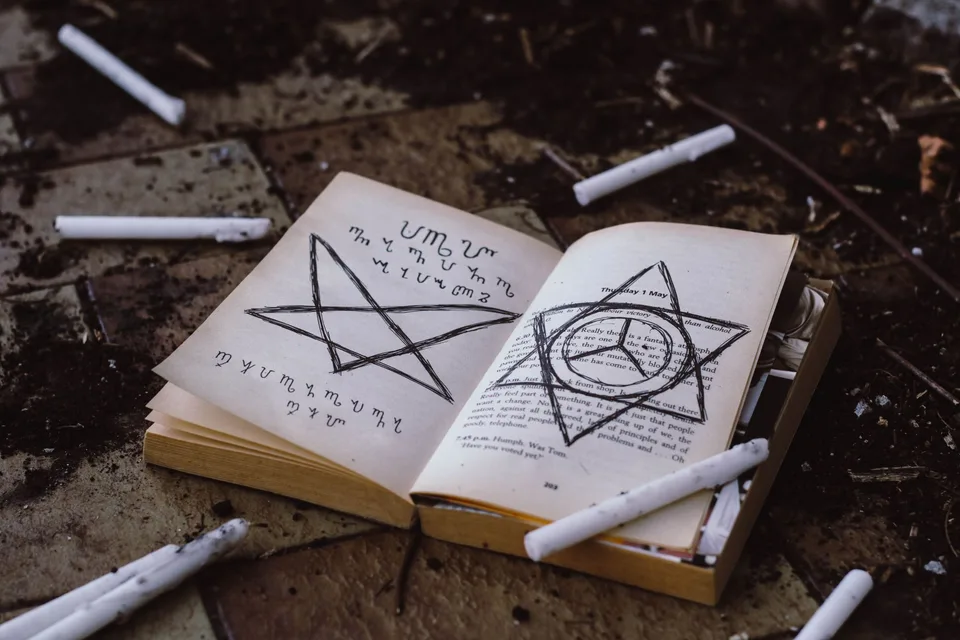 An old open book of symbols surrounded by candles on a stone floor