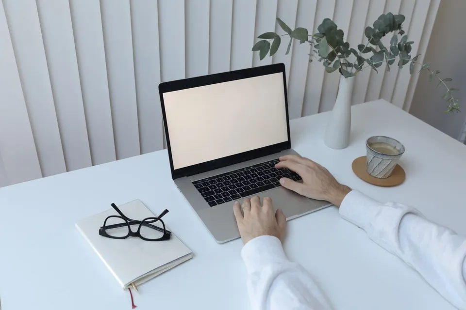 Writing a query letter on a laptop at a bright, modern desk