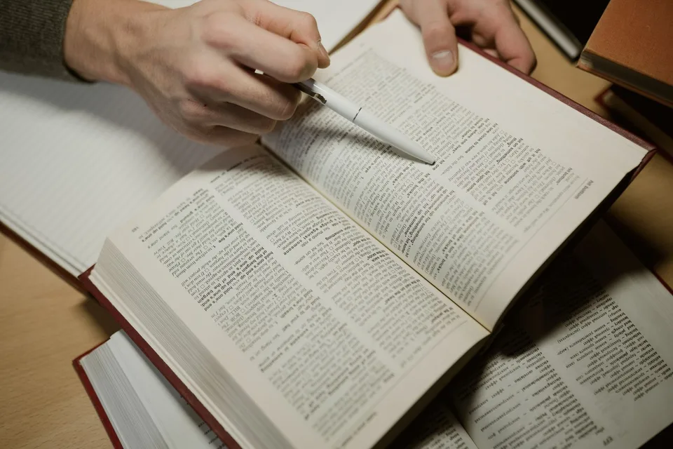 A hand pointing a pen at lines of text on a printed page during a close revision read